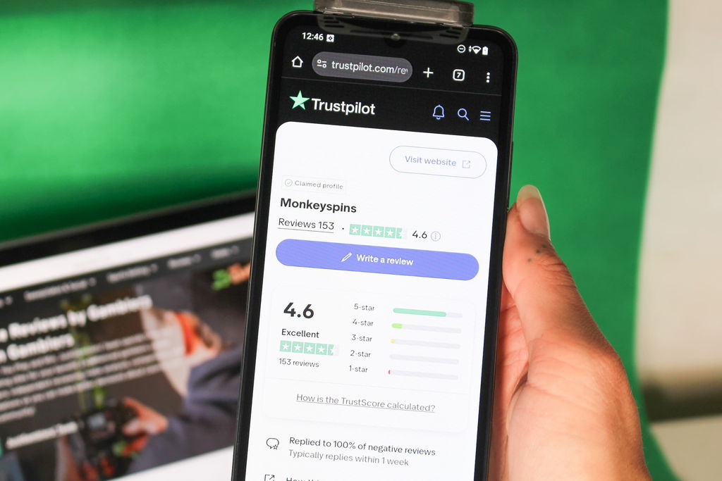Angela Zillich holding an iPhone with the Monkey Spins casino Trustpilot page loaded on the webpage.
