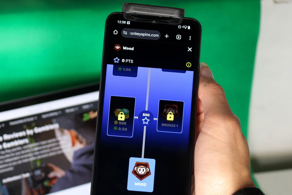 Angela Zillich holding an iPhone with the Monkey Spins casino VIP page loaded on the webpage.