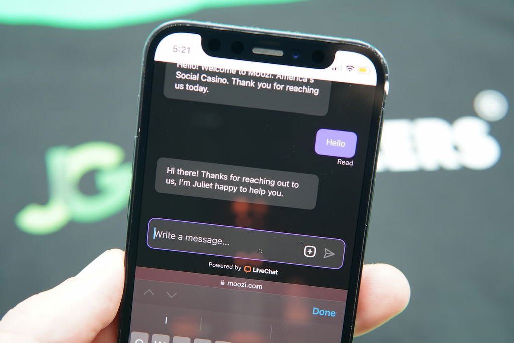 Patrik Lidin holding an iPhone with the Moozi casino support page loaded on the webpage.