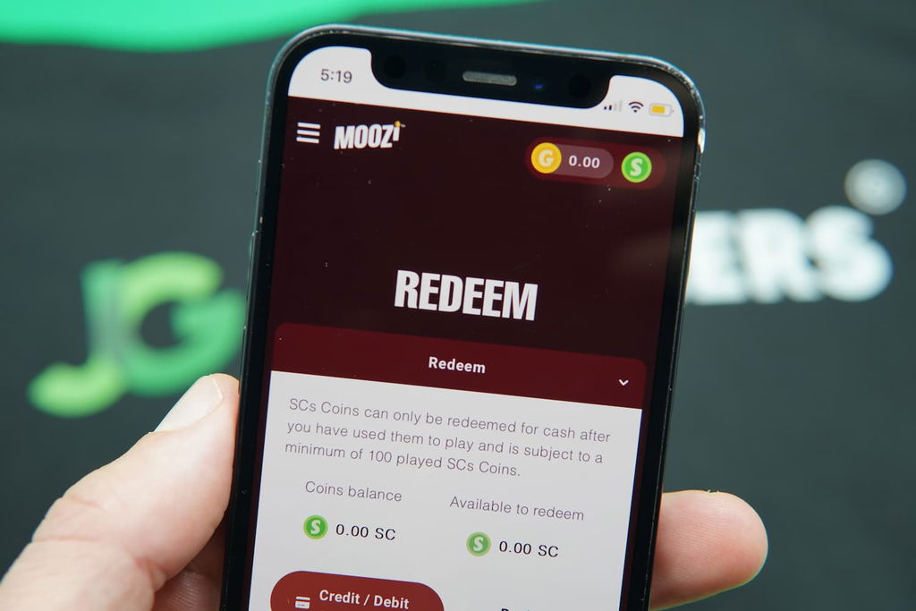 Patrik Lidin holding an iPhone with the Moozi casino redemptions page loaded on the webpage.