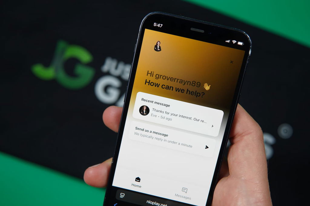 Patrik Lidin holding an iPhone with the Nioplay casino support page loaded on the webpage.