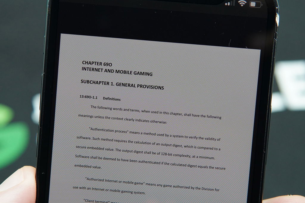 Photo of Patrik Lidin holding a .PDF showing NJDGE laws and provisions for NJ online casino bonuses.