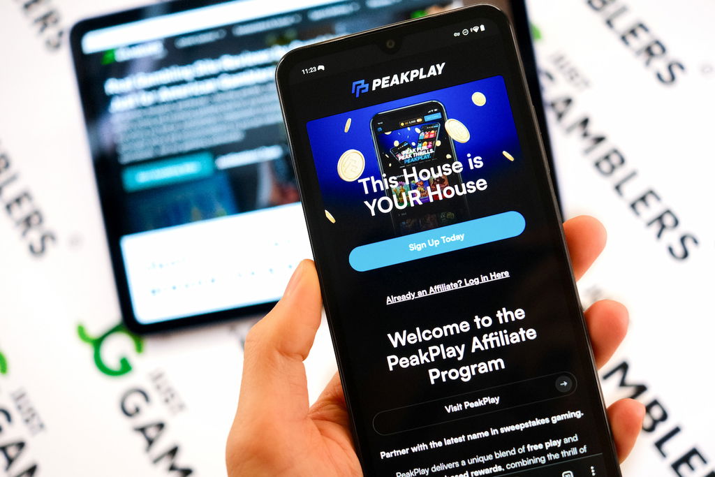 Angela Zillich holding an Android Phone with the PeakPlay casino Affiliate Program page loaded on the webpage.
