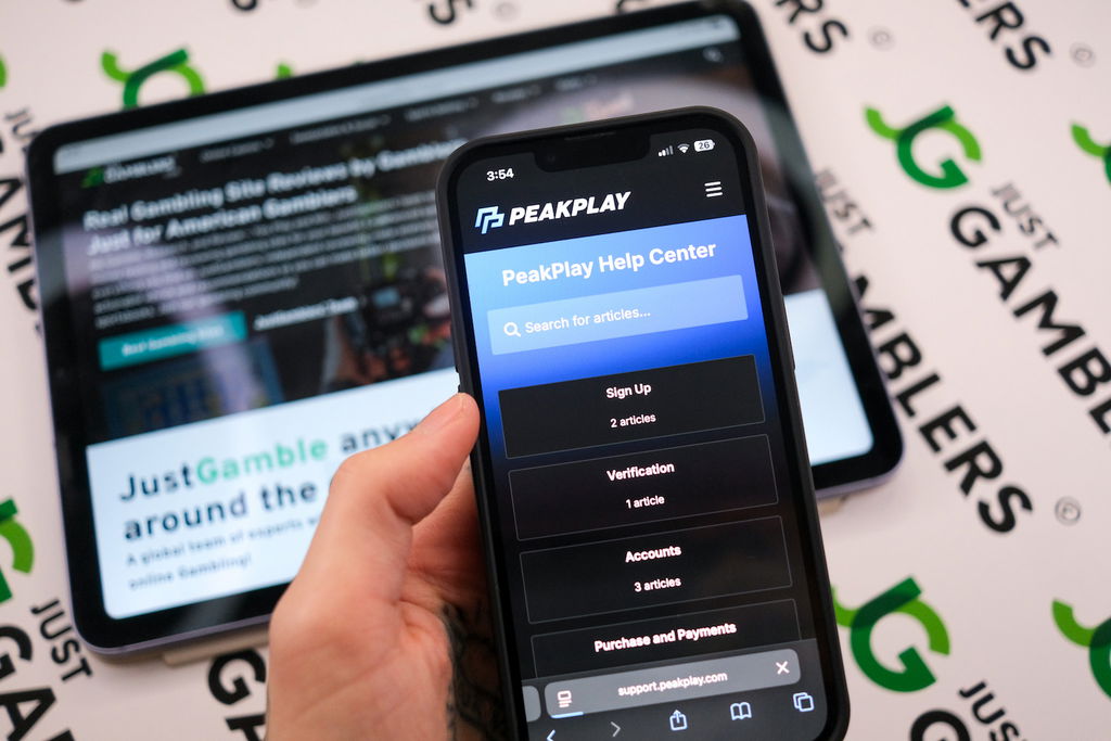 Angela Zillich holding an iPhone with the PeakPlay casino Customer Support page loaded on the webpage.