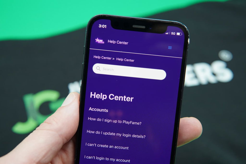 Patrik Lidin holding an iPhone with the PlayFame support page loaded on the webpage.