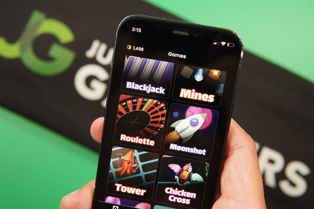 Patrik Lidin holding an iPhone with the Playnomic casino game library page loaded on the webpage.