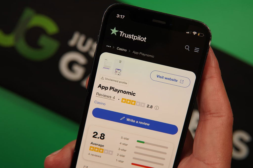 Patrik Lidin holding an iPhone with the Playnomic casino Trustpilot page loaded on the webpage.