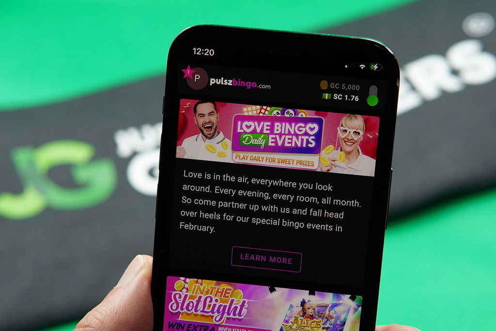 Patrik Lidin holding an iPhone with the Pulsz Bingo rewards page loaded on the webpage.