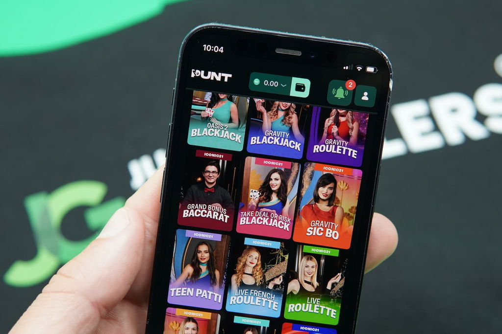 Patrik Lidin holding an iPhone with the Punt casino game library page loaded on the webpage.