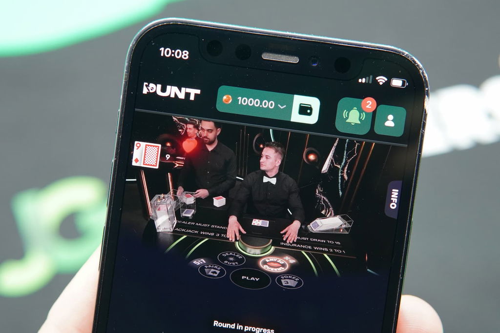 Patrik Lidin holding an iPhone with the Punt casino in-game mobile page loaded on the webpage.
