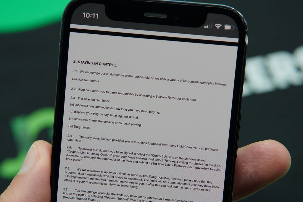 Patrik Lidin holding an iPhone with the Punt casino responsible gambling page loaded on the webpage.