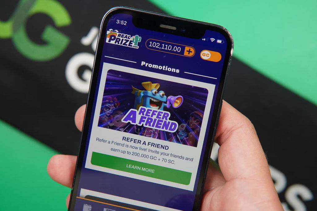 Patrik Lidin holding an iPhone with the RealPrize casino promotions page loaded on the webpage.