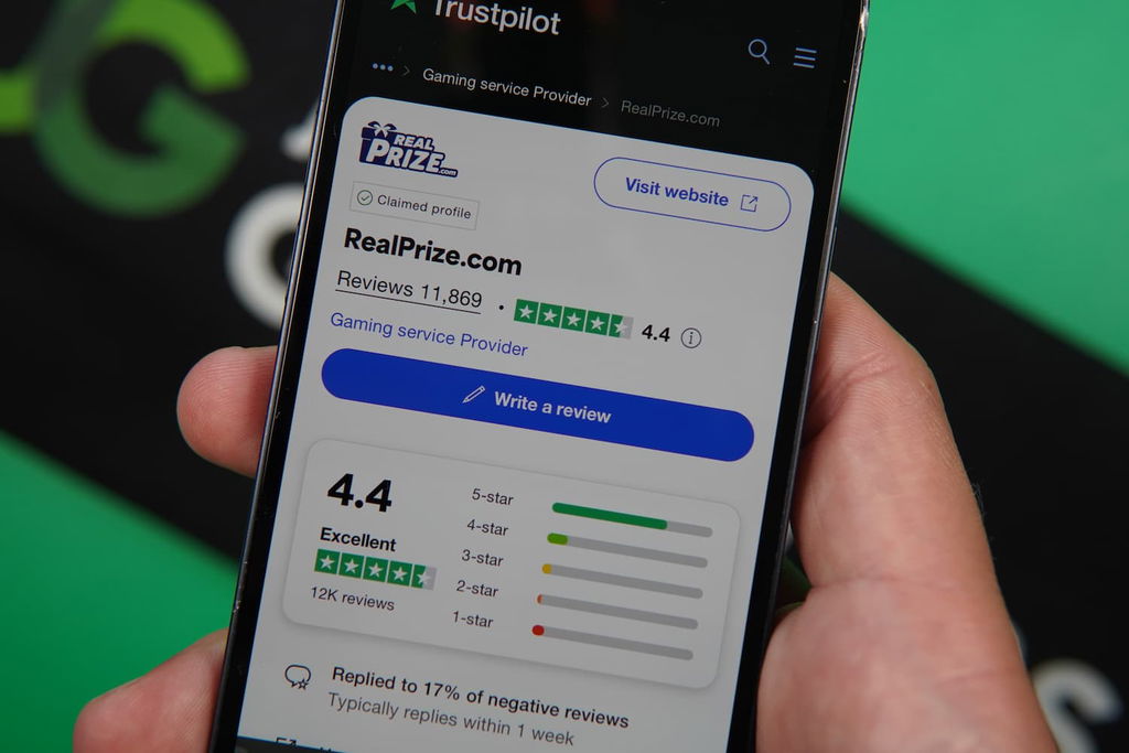 Patrik Lidin holding an iPhone with the RealPrize casino Trustpilot rating page loaded on the webpage.