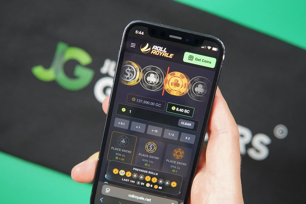 Patrik Lidin holding an iPhone with the Roll Royale casino landing page loaded on the webpage.