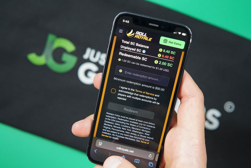 Patrik Lidin holding an iPhone with the Roll Royale casino redemptions page loaded on the webpage.