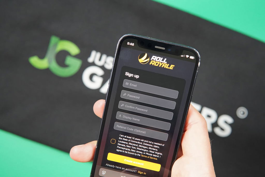 Patrik Lidin holding an iPhone with the Roll Royale casino registration page loaded on the webpage.