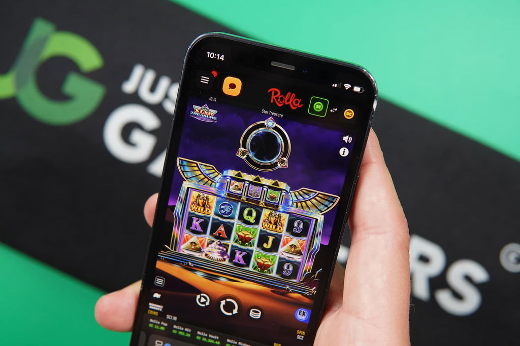 Patrik Lidin holding an iPhone with the Rolla casino in-game mobile page loaded on the webpage.