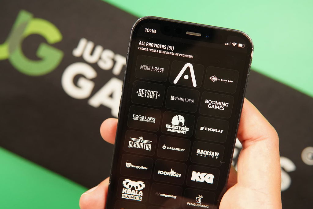 Patrik Lidin holding an iPhone with the Rolla casino software providers page loaded on the webpage.