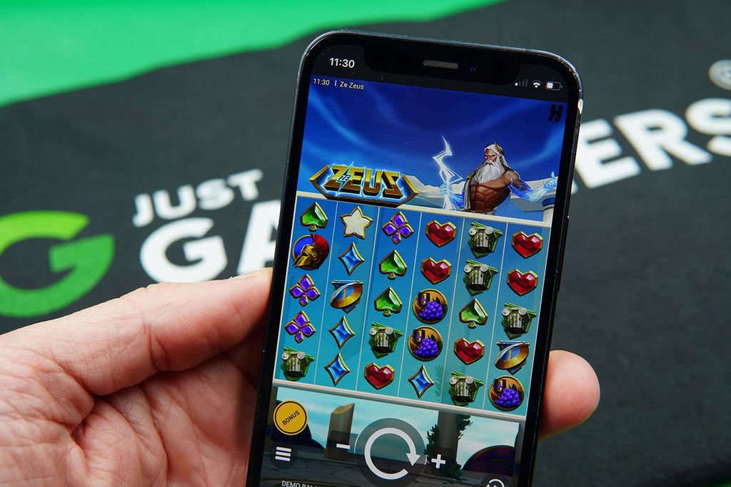 Patrik Lidin holding an iPhone with Runestake casino game Ze Zeus showing.