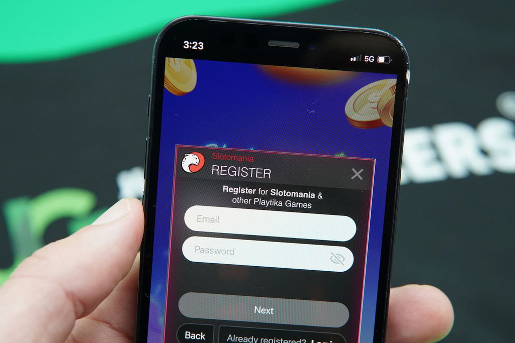 Patrik Lidin holding an iPhone with the Slotomania casino registration page loaded on the webpage.