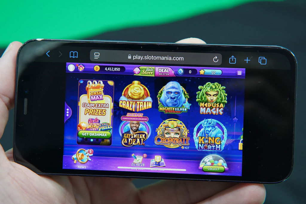 Patrik Lidin holding an iPhone with the Slotomania casino landing page loaded on the webpage.