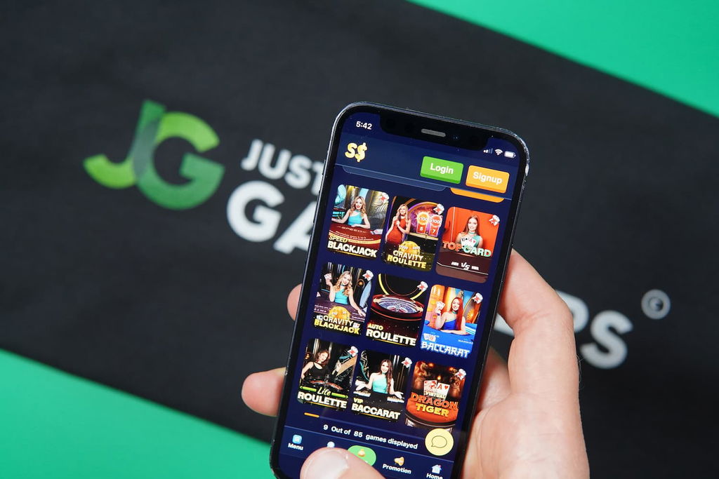 Patrik Lidin holding an iPhone with the SpeedSweeps casino game library live casino page loaded on the webpage.