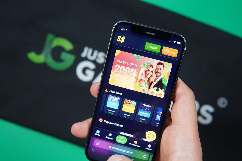 Patrik Lidin holding an iPhone with the SpeedSweeps casino landing page loaded on the webpage.