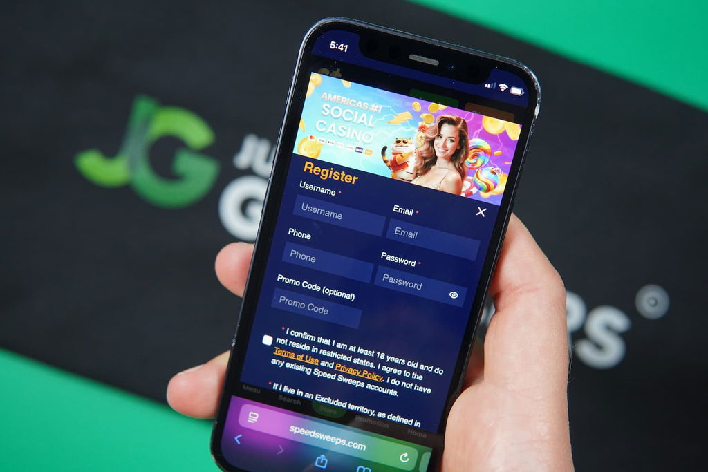 Patrik Lidin holding an iPhone with the SpeedSweeps casino registration page loaded on the webpage.