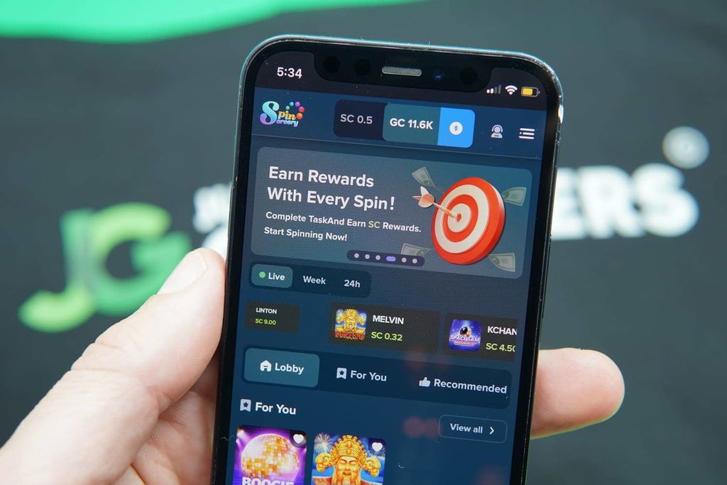 Patrik Lidin holding an iPhone with the Spin Sorcery casino landing page loaded on the webpage.
