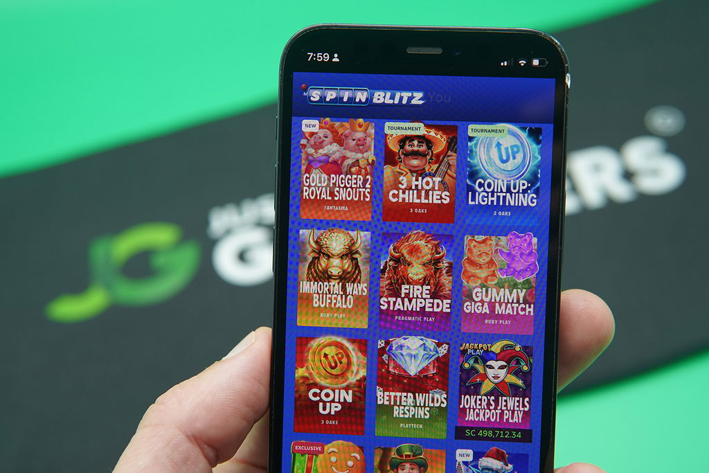 Patrik Lidin holding an iPhone with SpinBlitz game library showing.