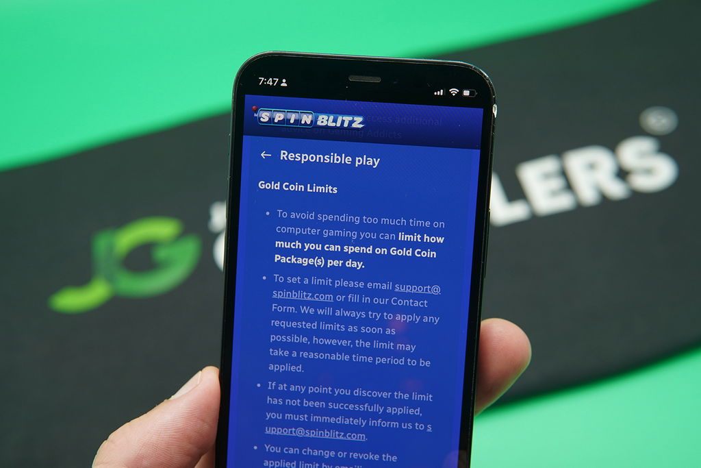 Patrik Lidin holding an iPhone with the SpinBlitz responsible gambling page showing.