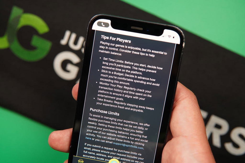Patrik Lidin holding an iPhone with the Spinfinite casino Responsible Gaming page loaded on the webpage.