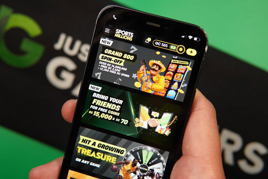 Patrik Lidin holding an iPhone with the Sports Millions sweepstakes casino promotions page loaded on the webpage.