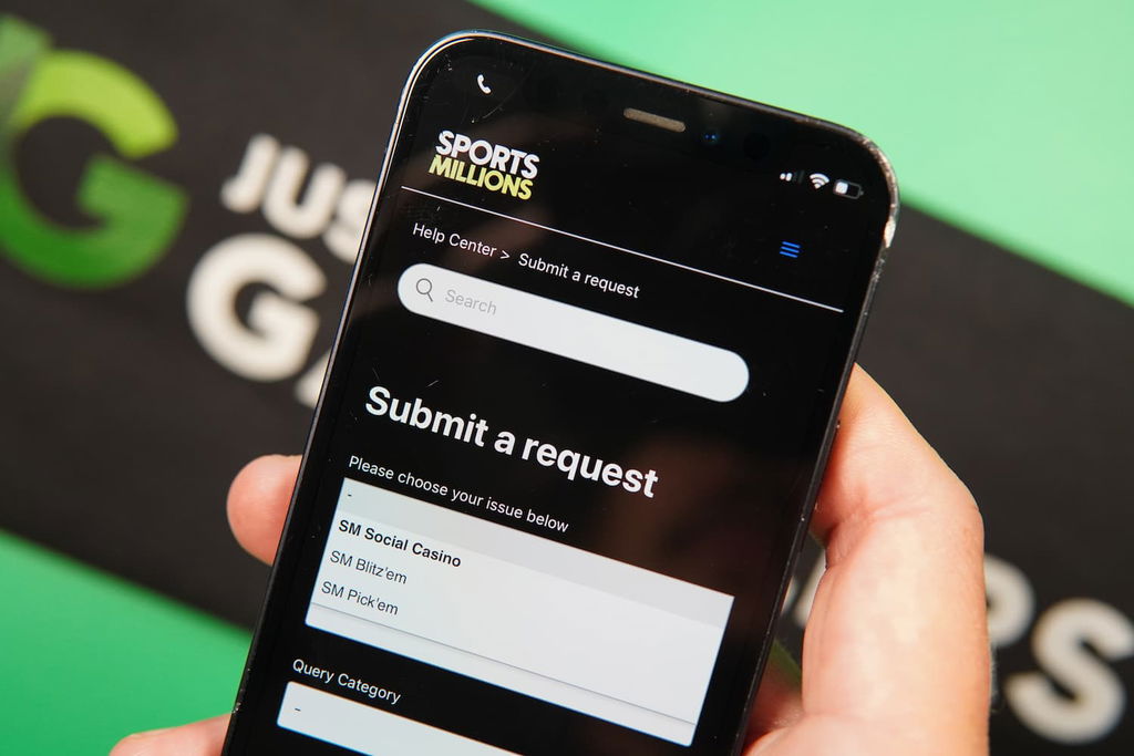Patrik Lidin holding an iPhone with the Sports Millions sweepstakes casino support page loaded on the webpage.