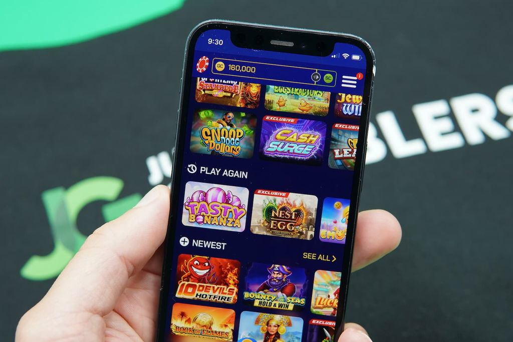 Patrik Lidin holding an iPhone with the Sportzino casino game library page loaded on the webpage.