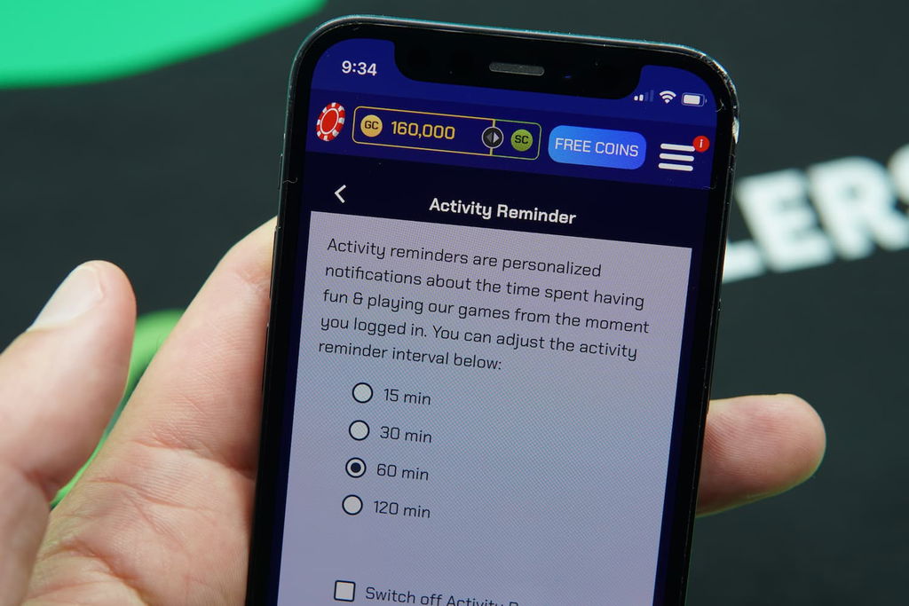 Patrik Lidin holding an iPhone with the Sportzino casino responsible gambling page loaded on the webpage.