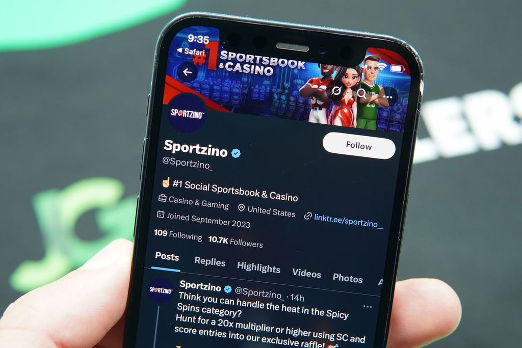 Patrik Lidin holding an iPhone with the Sportzino casino X page loaded on the webpage.