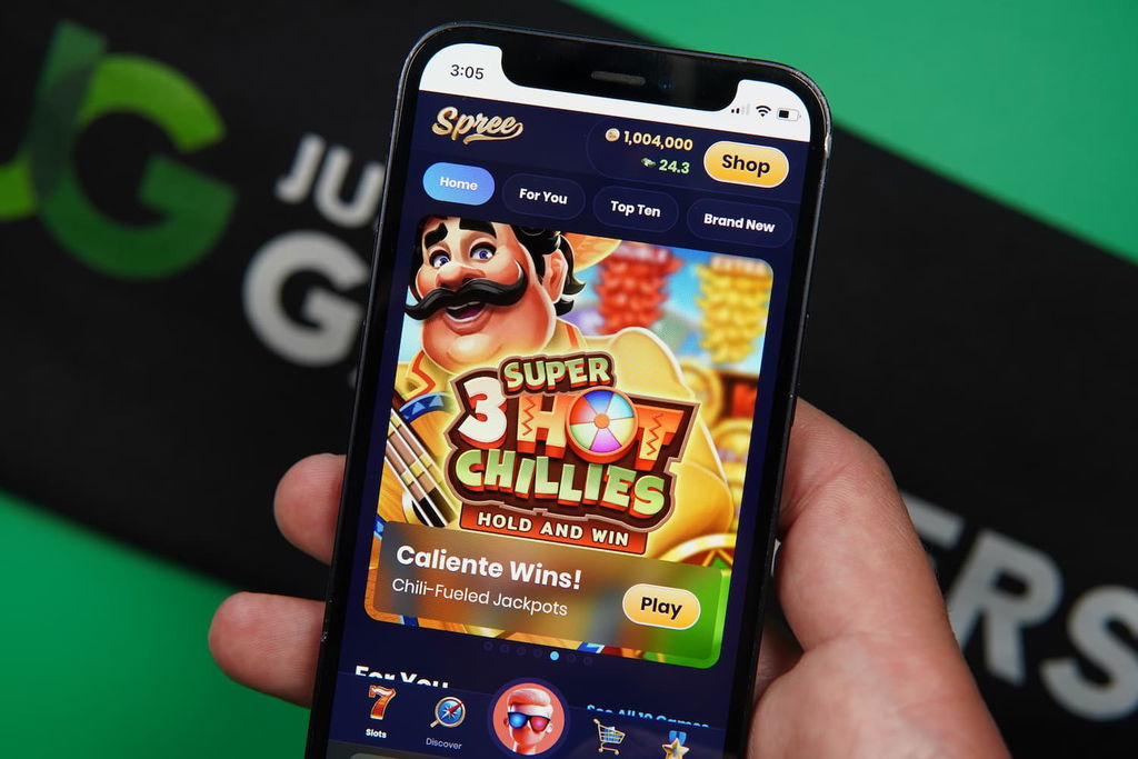 Patrik Lidin holding an iPhone with the Spree casino landing page loaded on the webpage.