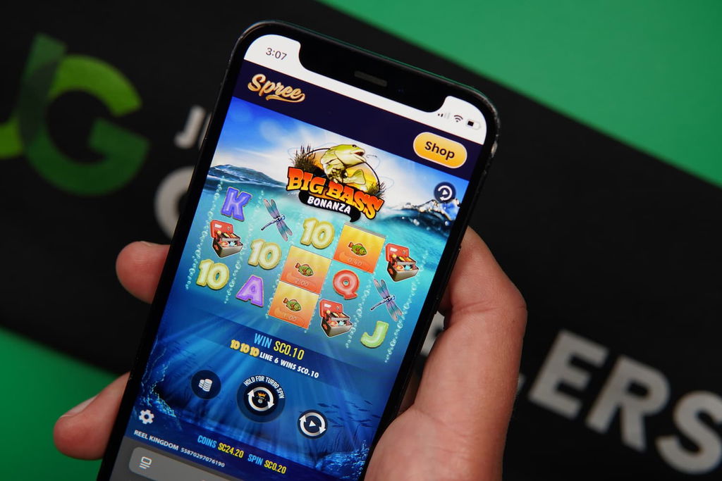 Patrik Lidin holding an iPhone with the Spree casino mobile in-game page loaded on the webpage.