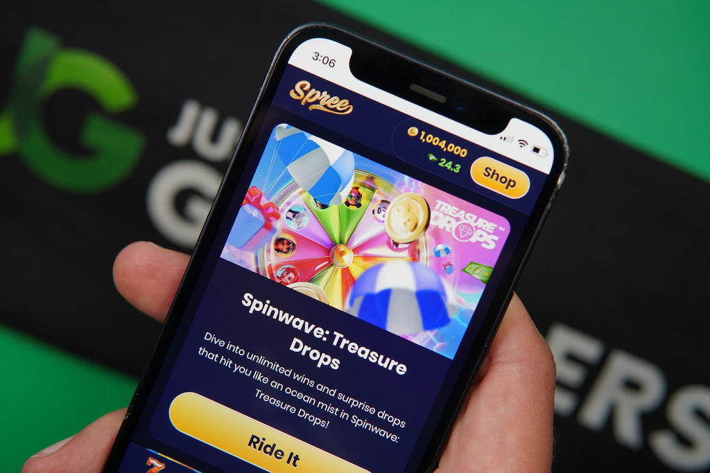 Patrik Lidin holding an iPhone with the Spree casino promotions page loaded on the webpage.