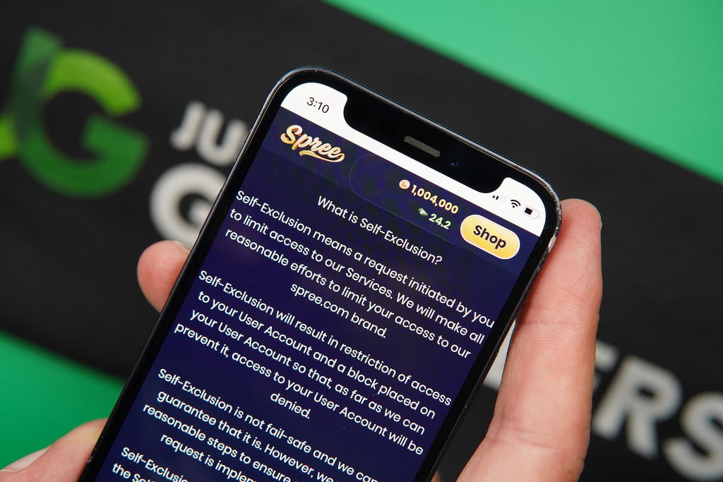 Patrik Lidin holding an iPhone with the Spree casino responsible gaming page loaded on the webpage.