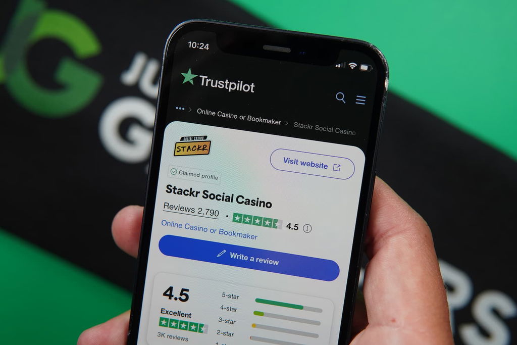 Patrik Lidin holding an iPhone with the Stackr casino Trustpilot rating page loaded on the webpage.