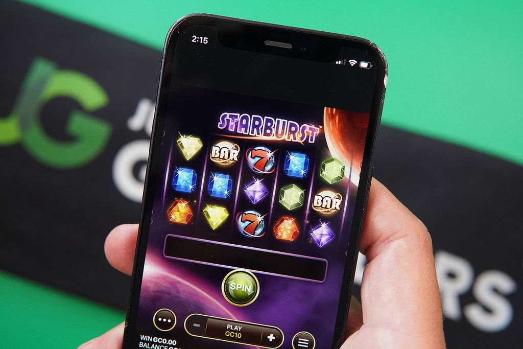 Photo of Patrik Lidin holding iPhone with Starburst game to clear no deposit bonus wagering requirements.