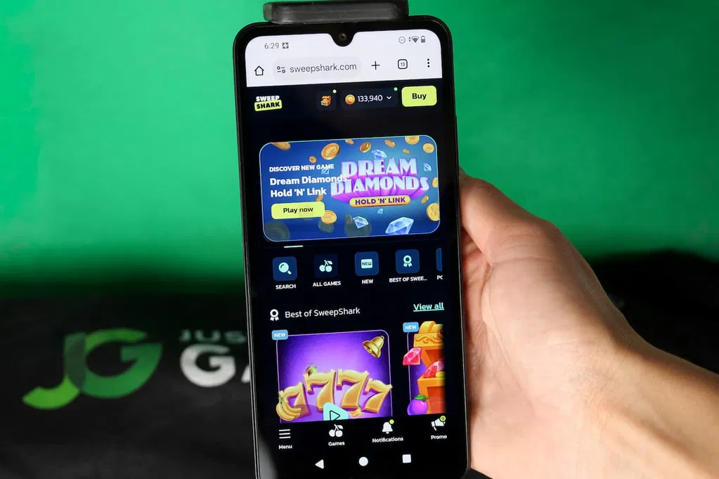 Angela Zillich holding an iPhone with the SweepShark casino landing page loaded on the webpage.