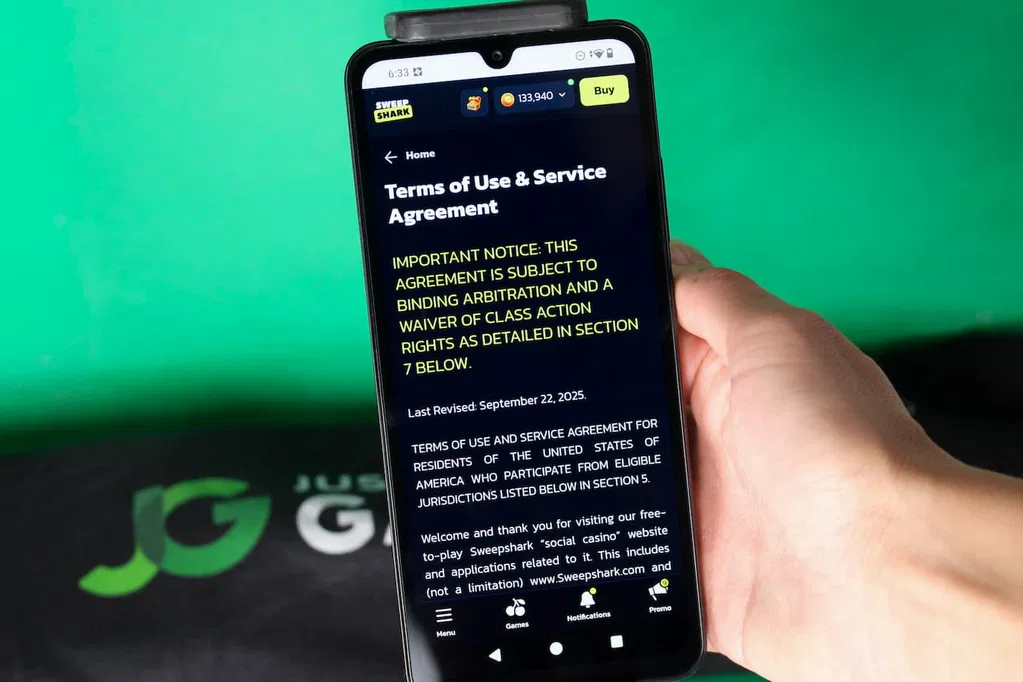 Angela Zillich holding an iPhone with the SweepShark casino Terms of Use page loaded on the webpage.