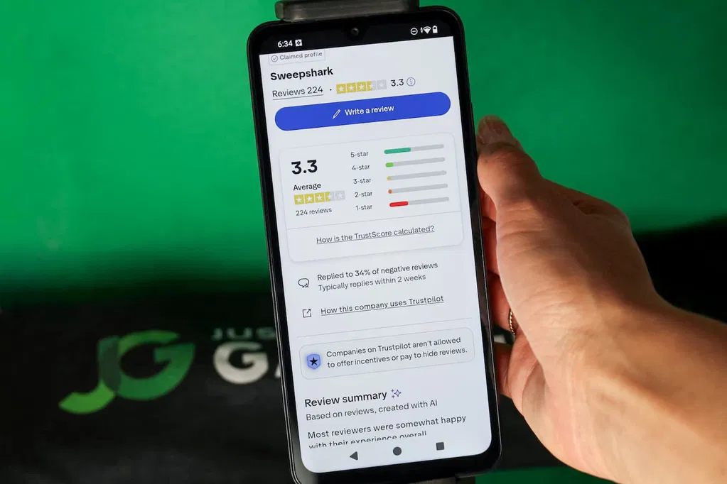 Angela Zillich holding an iPhone with the SweepShark casino Trustpilot ratings page loaded on the webpage.