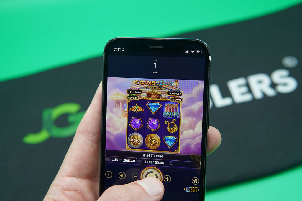 Patrik Lidin holding an iPhone with Sweeptastic casino game Coins of Zeus showing.