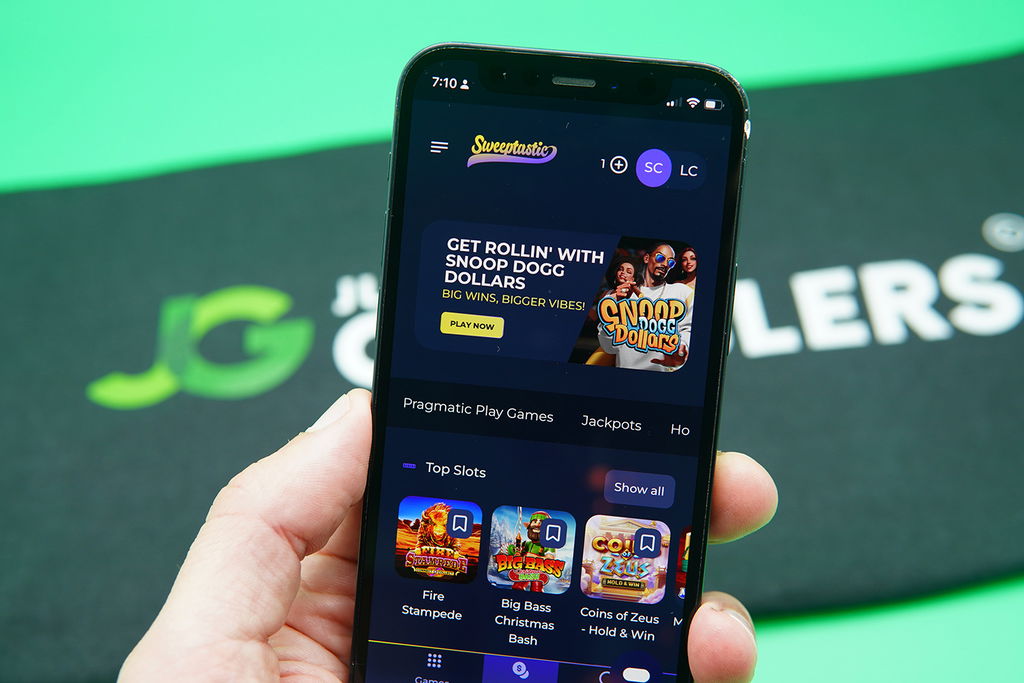 Patrik Lidin holding an iPhone with the Sweeptastic casino loaded on the webpage.