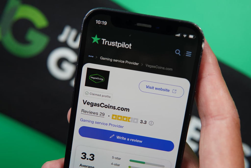 Patrik Lidin holding an iPhone with the Vegas Coins casino Trustpilot rating page loaded on the webpage.
