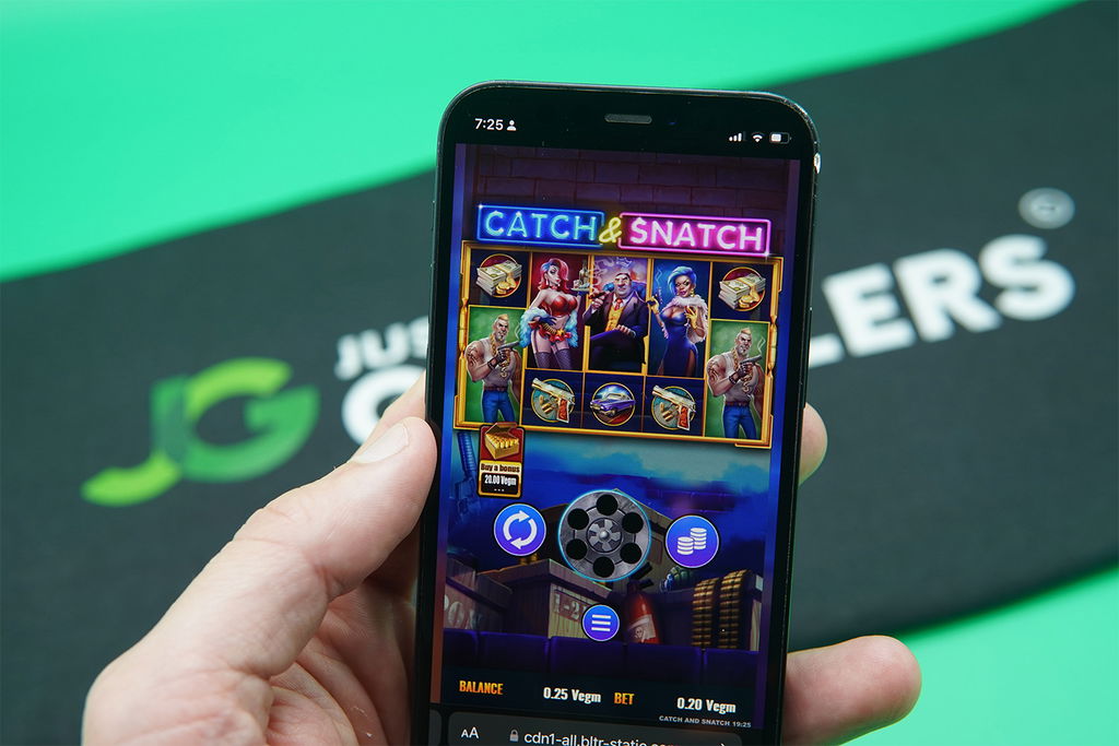 Patrik Lidin holding an iPhone with Vegas Gems casino game Catch & Snatch showing.